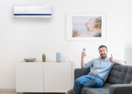 Man sits in seat with thumb up and remote control to operate air conditioner with