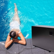 Une femme gît dans une piscine à côté d'une pompe à chaleur