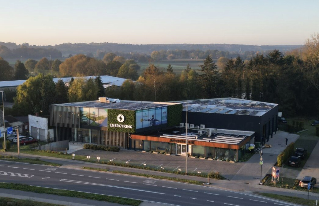 Modern office building with ENERGYKING signage, glass entrance, and adjacent parking along a tree-lined road at dusk/dawn.