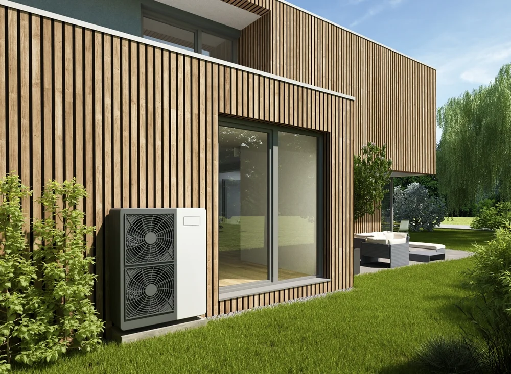 Extérieur moderne d'une maison revêtue de bois, avec une grande porte vitrée, un climatiseur extérieur et une pelouse verte à proximité.